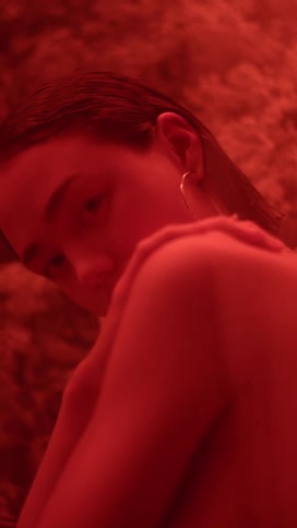 A woman is standing in front of flowers in a room illuminated with red light