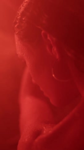 A woman waves her arms around in a red hued room