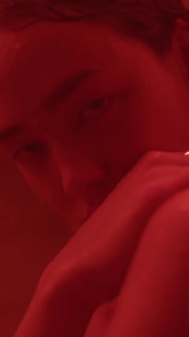 A woman poses in room lit up with a red light