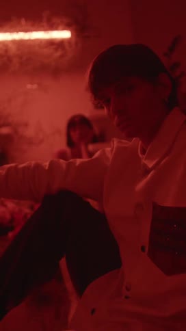 A sad looking man sits in a room in front of a woman resting her head in her hand