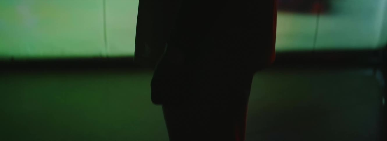 Man stands silhouetted against large digital screen in dark area