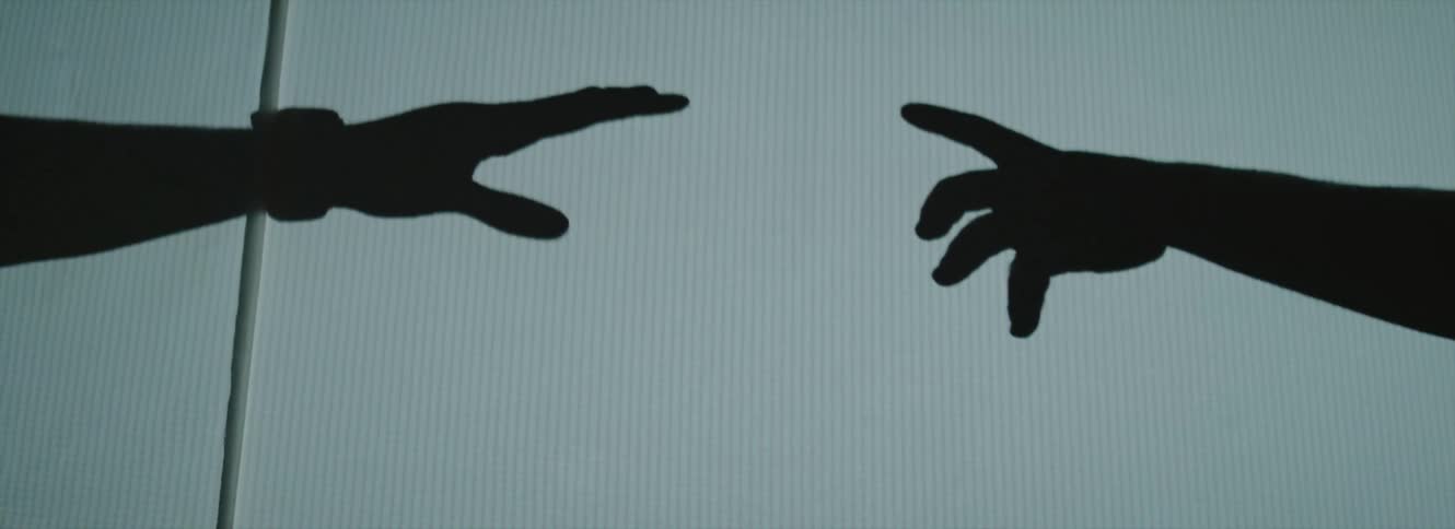 The silhouette of two outstretched arms and hands with fingers reaching