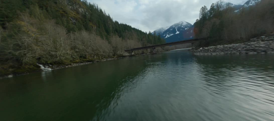 A river running through a forest with mountains in the distance