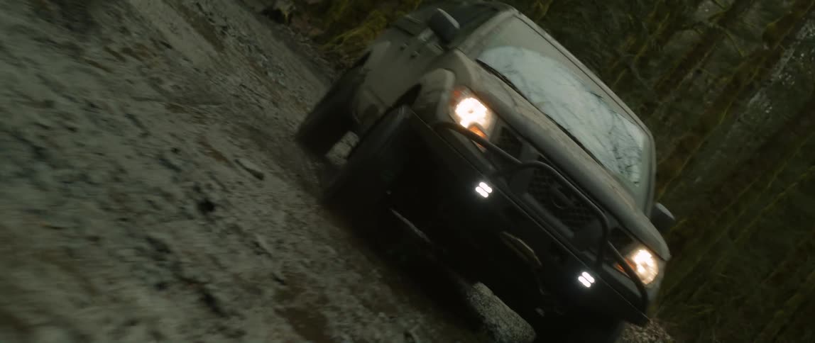 A car is driving off road in a wooded area