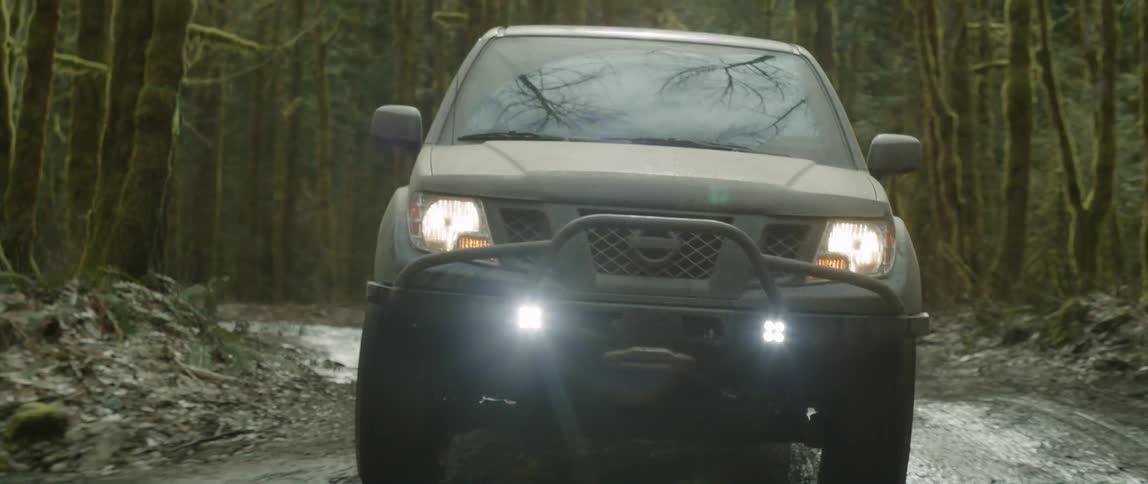 A car is driving through a forest area