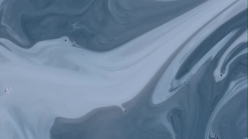 Cobalt blue liquid swirls as it blends with a lighter shade of the substance