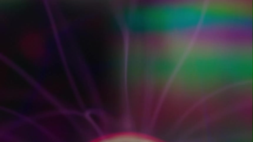 Electricity arcing from plasma ball causing a rainbow of color