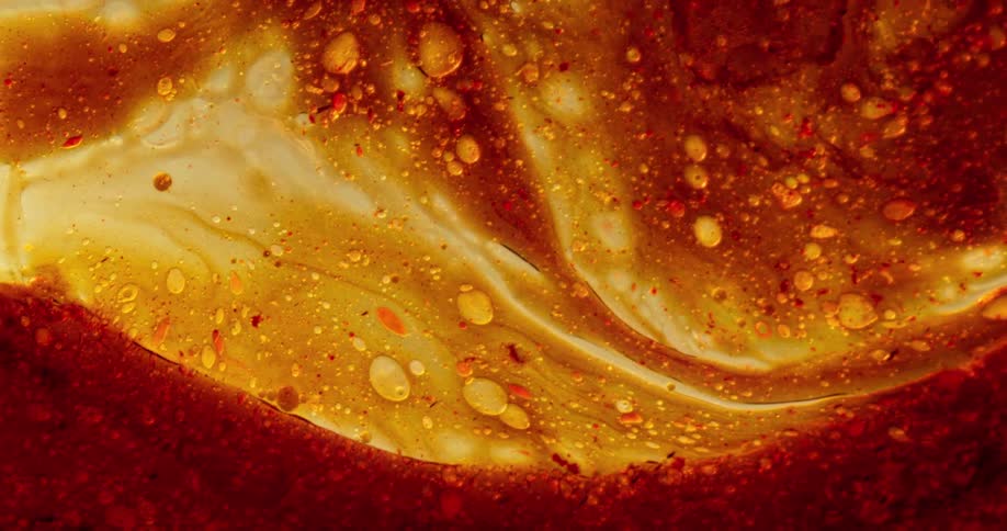 A closeup of an orange and red liquid flows and swirls smoothly