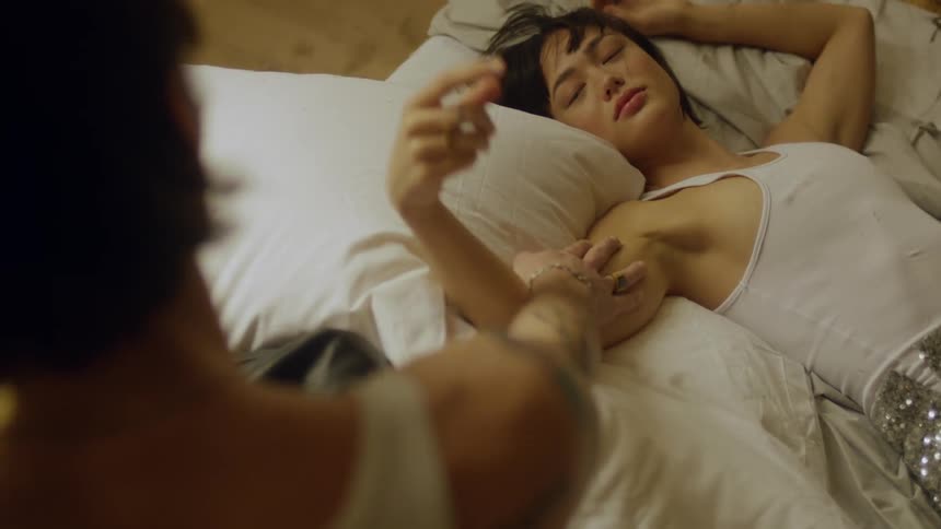A couple reach out and touch arms while lying in bed