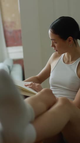 A woman sits and reads with her legs propped up