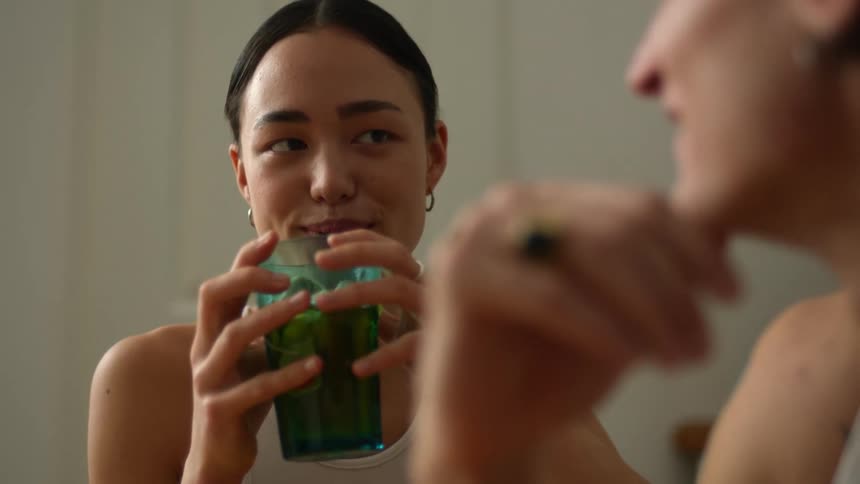 A woman holds a drink while chatting with her partner