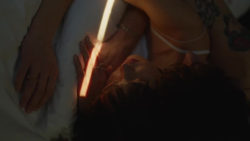 A beam of light crosses over a man and woman as they sleep