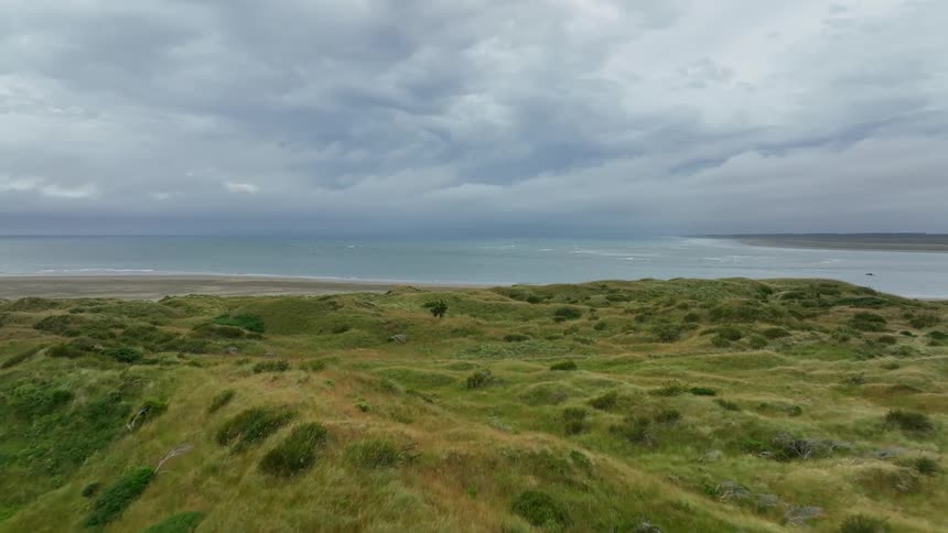 Aerial view of green hills overlooking coast on cloudy day