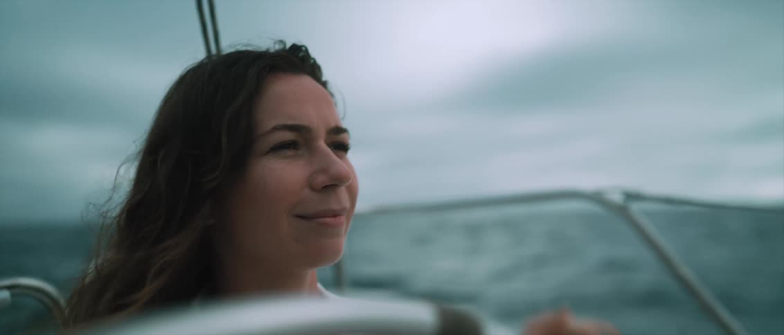 Woman with wavy hair drives yatch on cloudy day