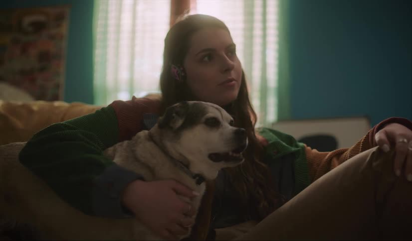 A woman hugs her dog while sitting together on the couch
