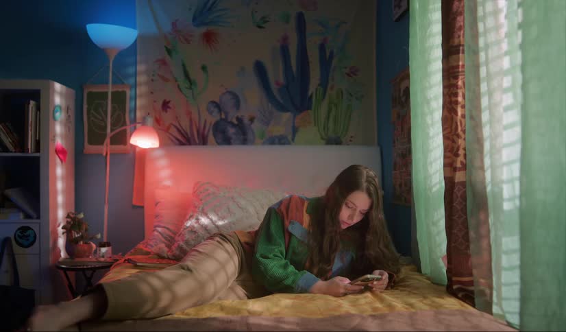 A teenage girl is lying on her bed and texting on her cell phone