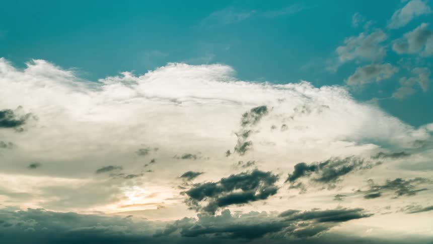 Time lapse of clouds at different heights moving over a blue sky at evening