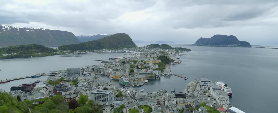 Ships and boats docked in Alesund, Norway with mountain in background