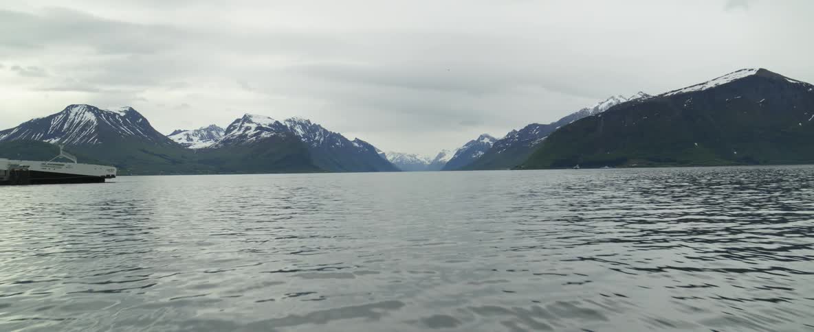 Drone flies over glacial water in Norway fjord land