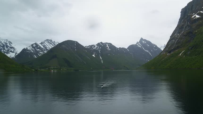 Aerial view of man rowing a boat in dramatic scenery in Norway fjords