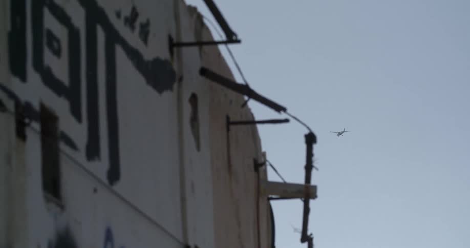 A plane flies over a wall covered in graffiti