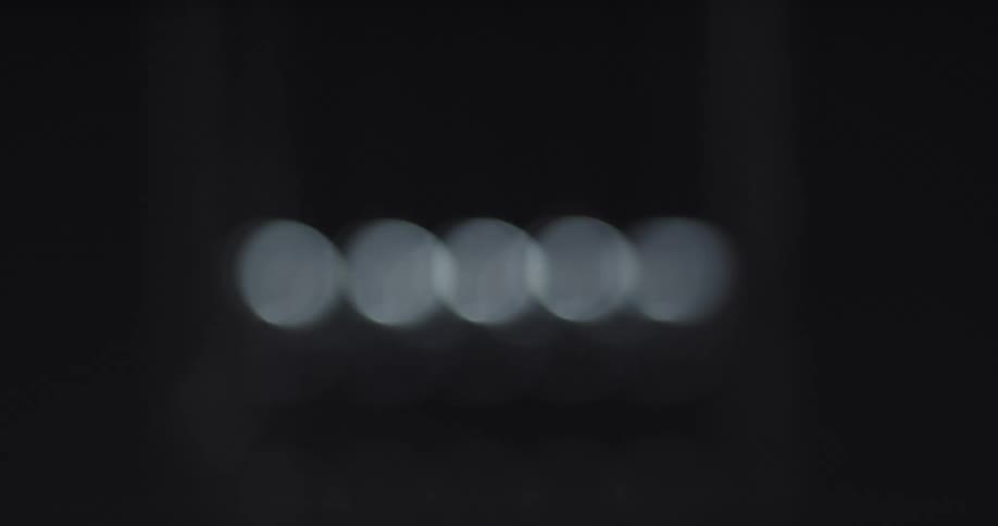 Out of focus footage of a newtons cradle pendulum on a dark room