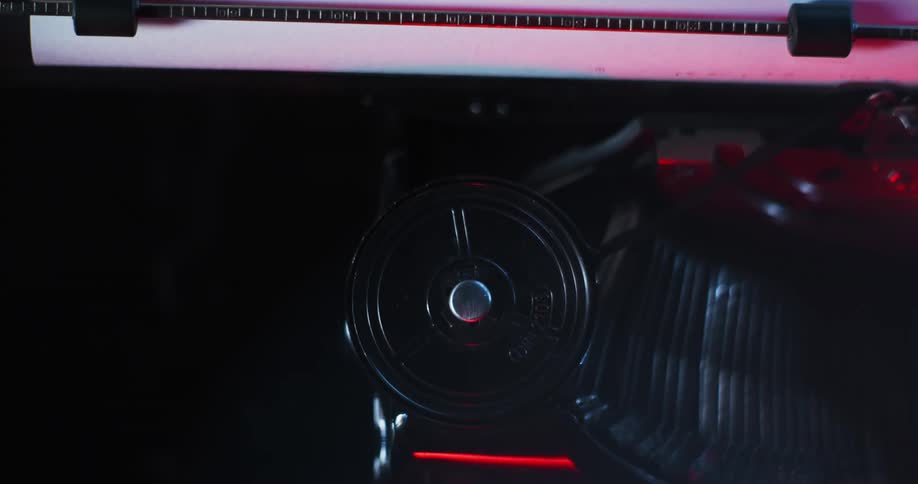 Light shines on the type bars and ribbon of an old typewriter as they move