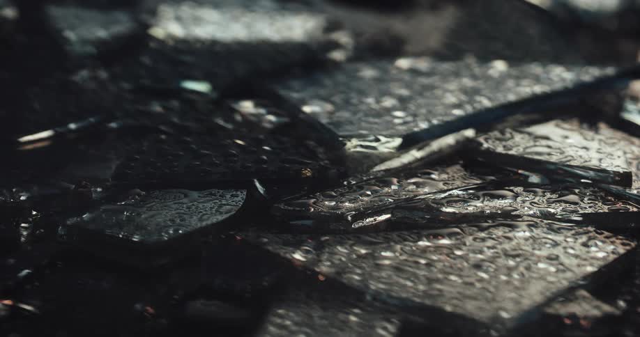 Close up of fragments of broken glass with police lights displaying on