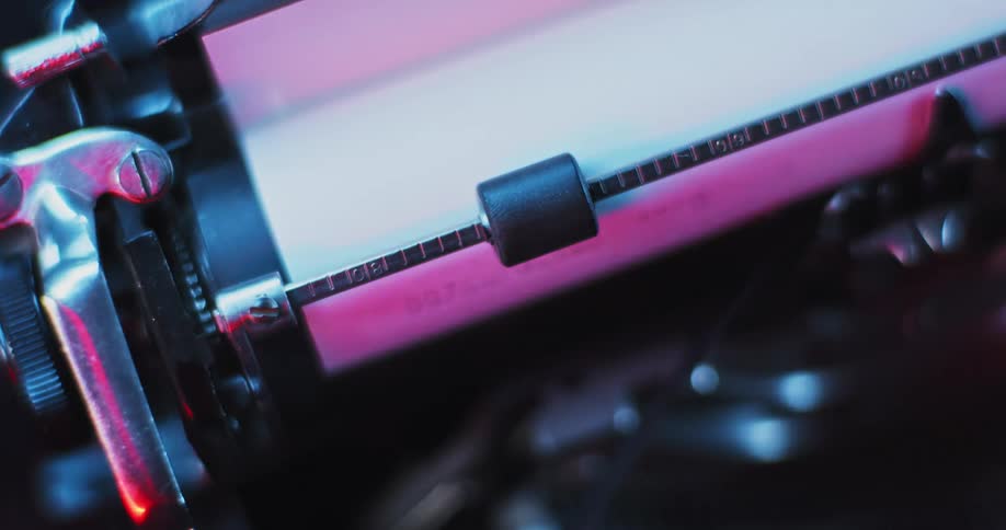 A light shines on the carriage of an old typewriter as it moves