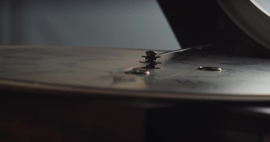 Arms of an analog wall clock resting on the floor inside a dark room