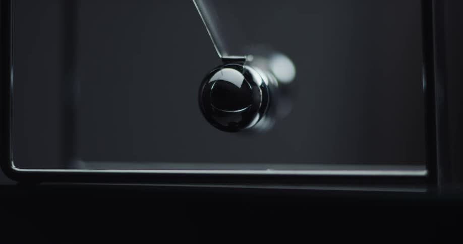 Metal balls are swinging back and forth hitting each other in a newtons cradle