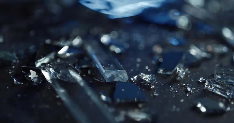 Close up of broken glass pieces with police lights displaying on