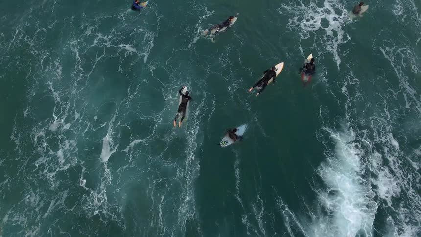 People are surfing in the rough water below