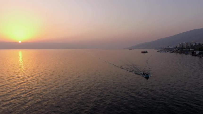 A boat floats on the ocean at sunset