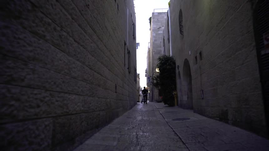 A man pushes a cart through an alley