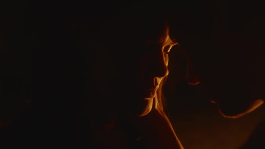 Woman with a sad expression on face illuminated by the fire touching her head against her boyfriends head