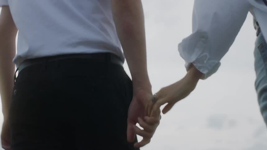 A couple hold hands and walk