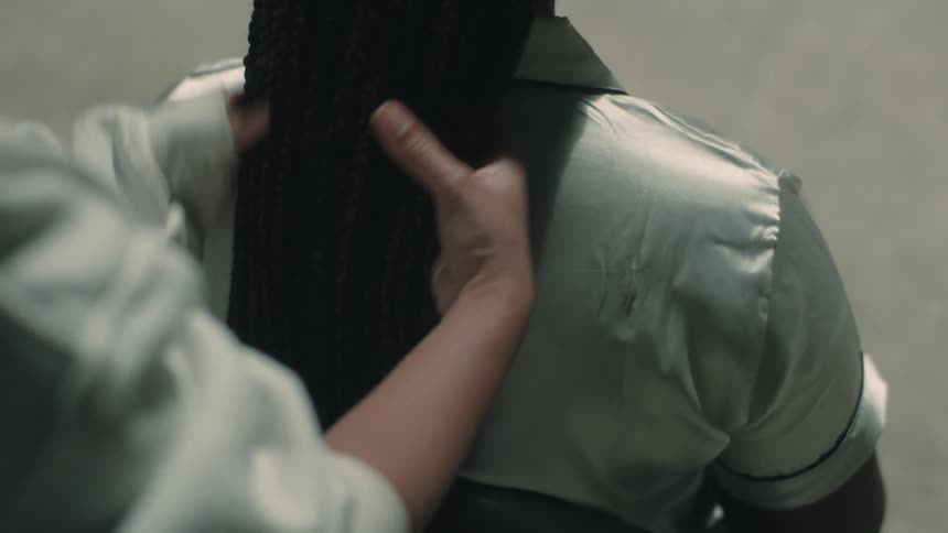 Hair stylist combs the hair of a woman sitting on a folding chair
