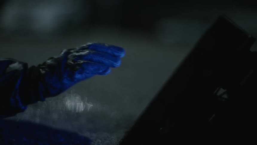 Person wearing a glove touches screen in dark area