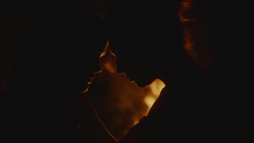 Couple standing in front of a campfire touching their heads in a romantic way