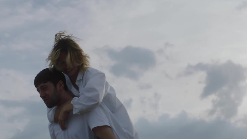 A woman jumps on her partners back for a piggyback ride