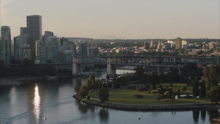 Aerial view of bridge over river next to Vancouver high rise buildings in the city at sunrise