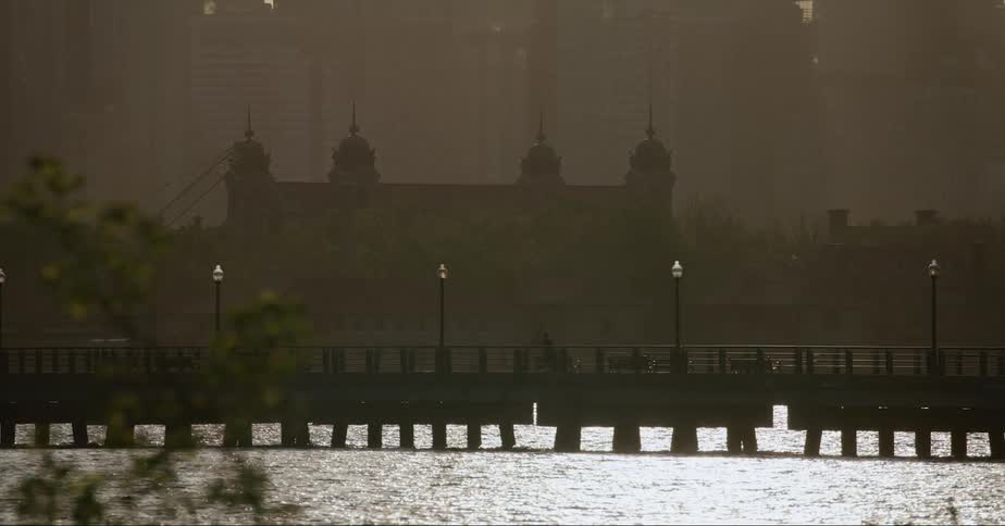 A person runs along a bridge that spans a river in a city