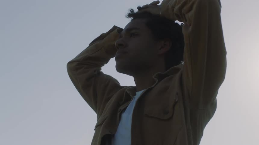 Young man locking his hands over his head while walking outdoors