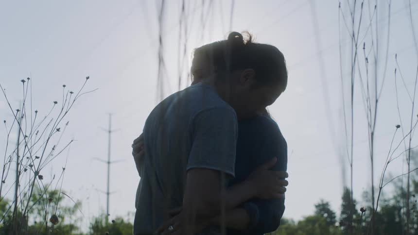 A couple is embracing as they stand outside