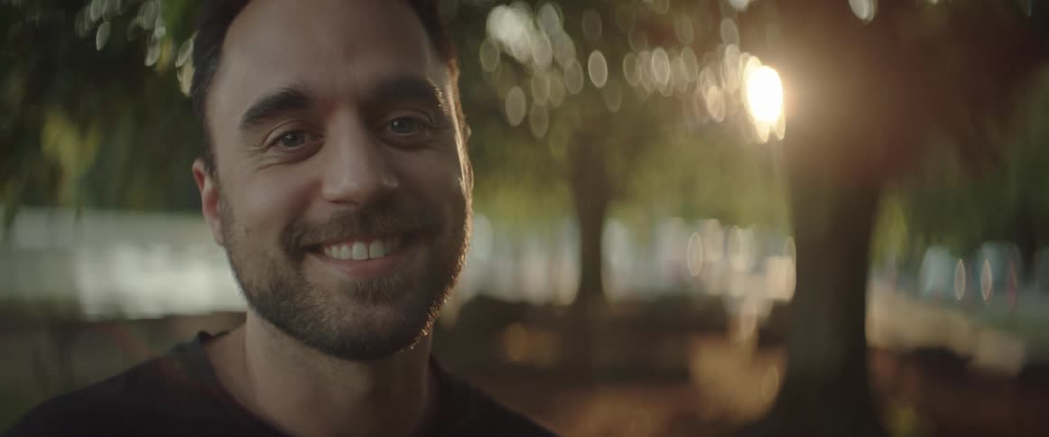 A man outside in the evening smiles during portrait