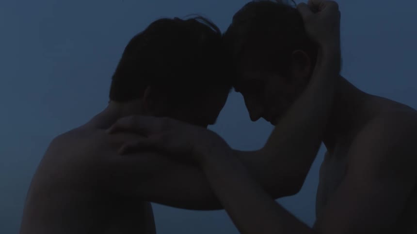 Two shirtless men embrace