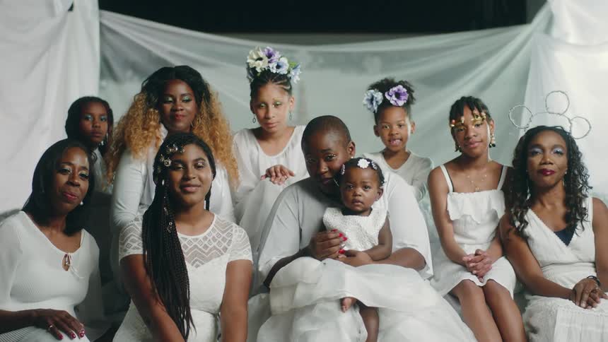 Group of African American women wearing white sitting together looking at the camera