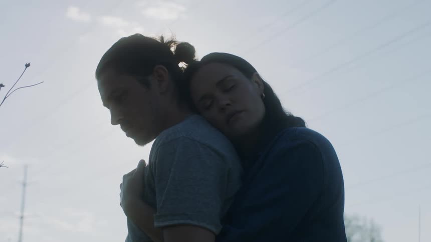 Woman resting her head on the back and hugging her boyfriend from behind while theyre standing outdoors at a sunny day