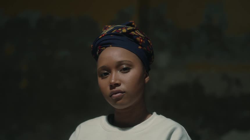 A black woman poses in a floral headscarf